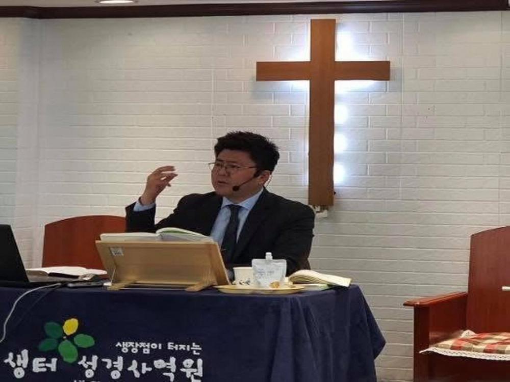 십자가 아래에서 성경을 펴고 말씀을 가르치는 모습